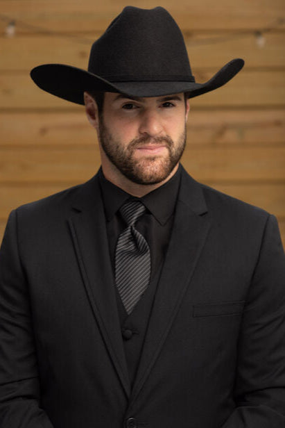man wearing black suit with black accessories styles with a black cowboy hat