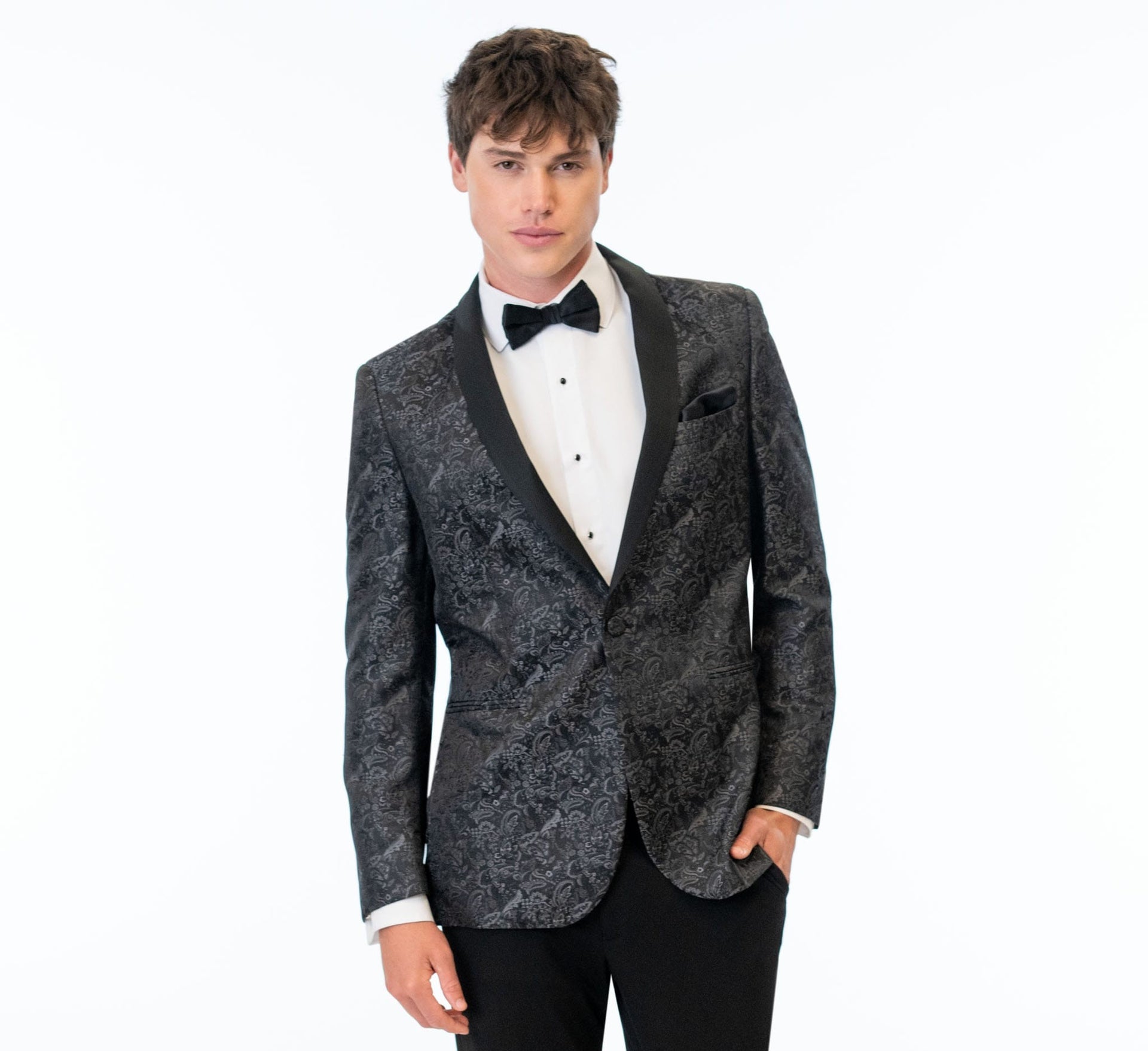 Man wearing a granite paisley tuxedo jacket with black bow tie on a white background