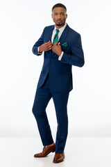 Man wearing Blue Performance Stretch Suit with a green tie and pocket square on a white background