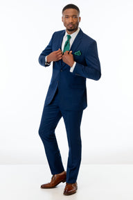 Man wearing Blue Performance Stretch Suit with a green tie and pocket square on a white background