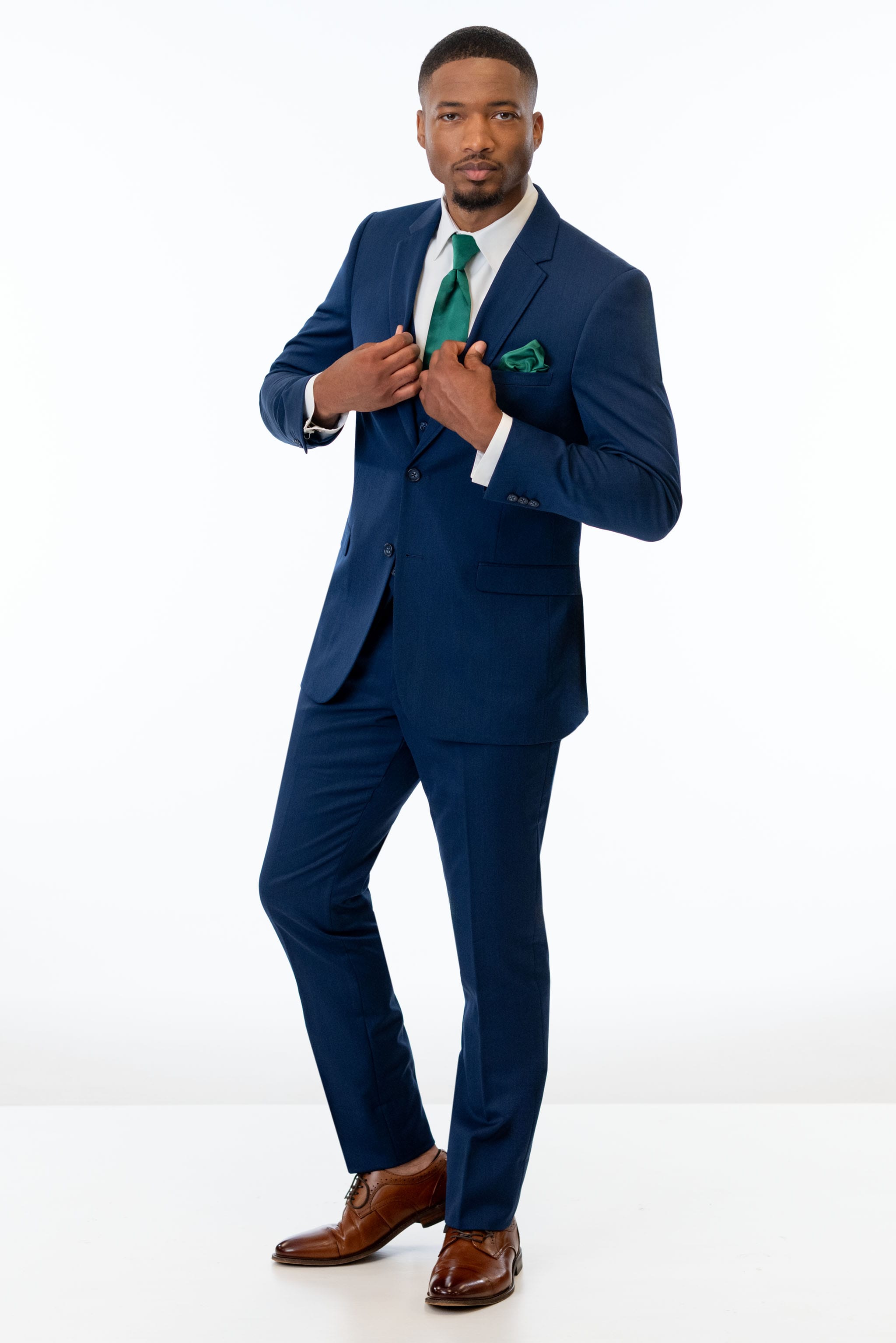 Man wearing Blue Performance Stretch Suit with a green tie and pocket square on a white background