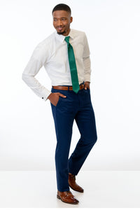 side view of man wearing Blue Performance Stretch Slim Fit Suit pants, white shirt, and emerald green tie