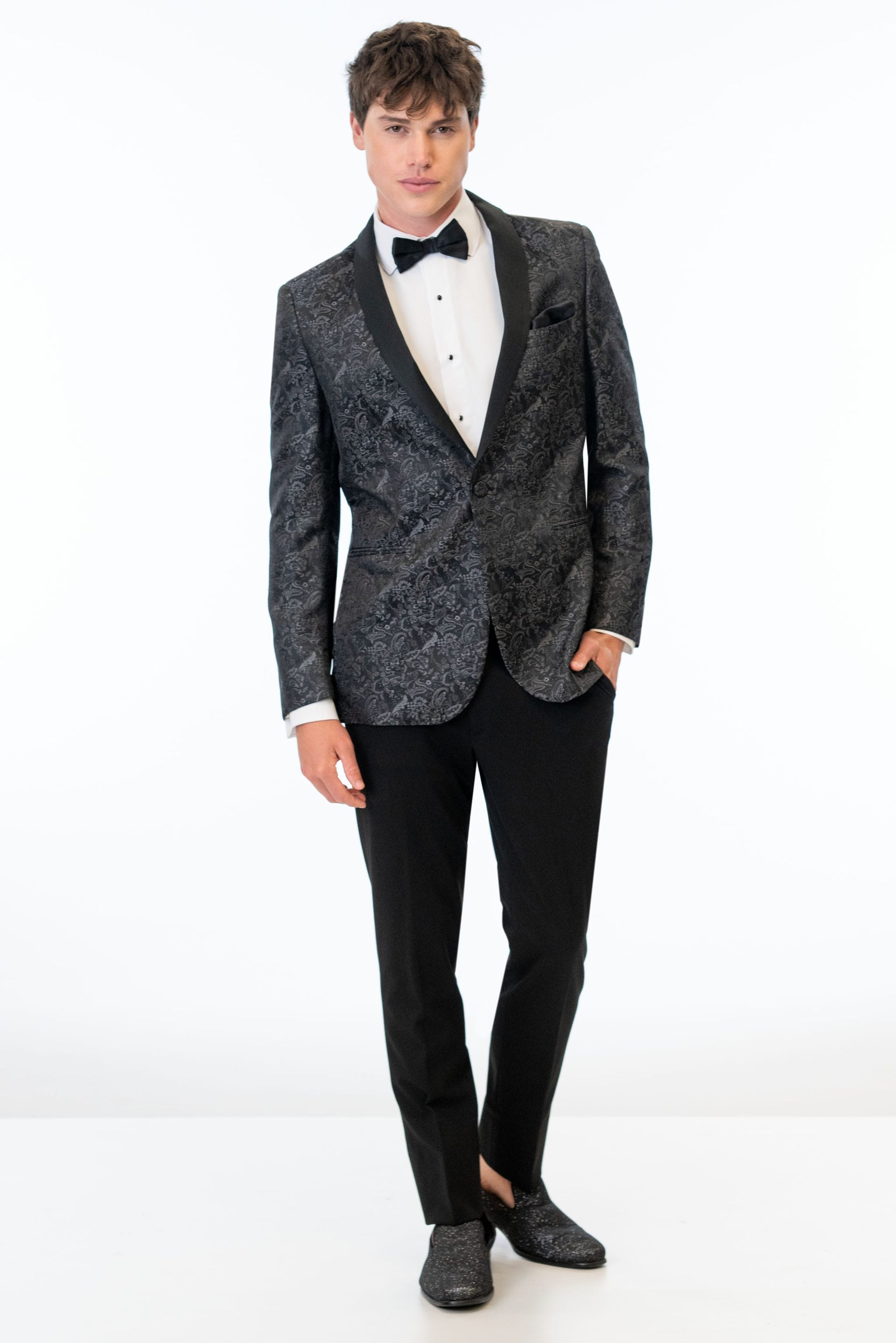 Man wearing Granite Paisley Tuxedo jacket, black pants, white shirt and black bow tie on a white background