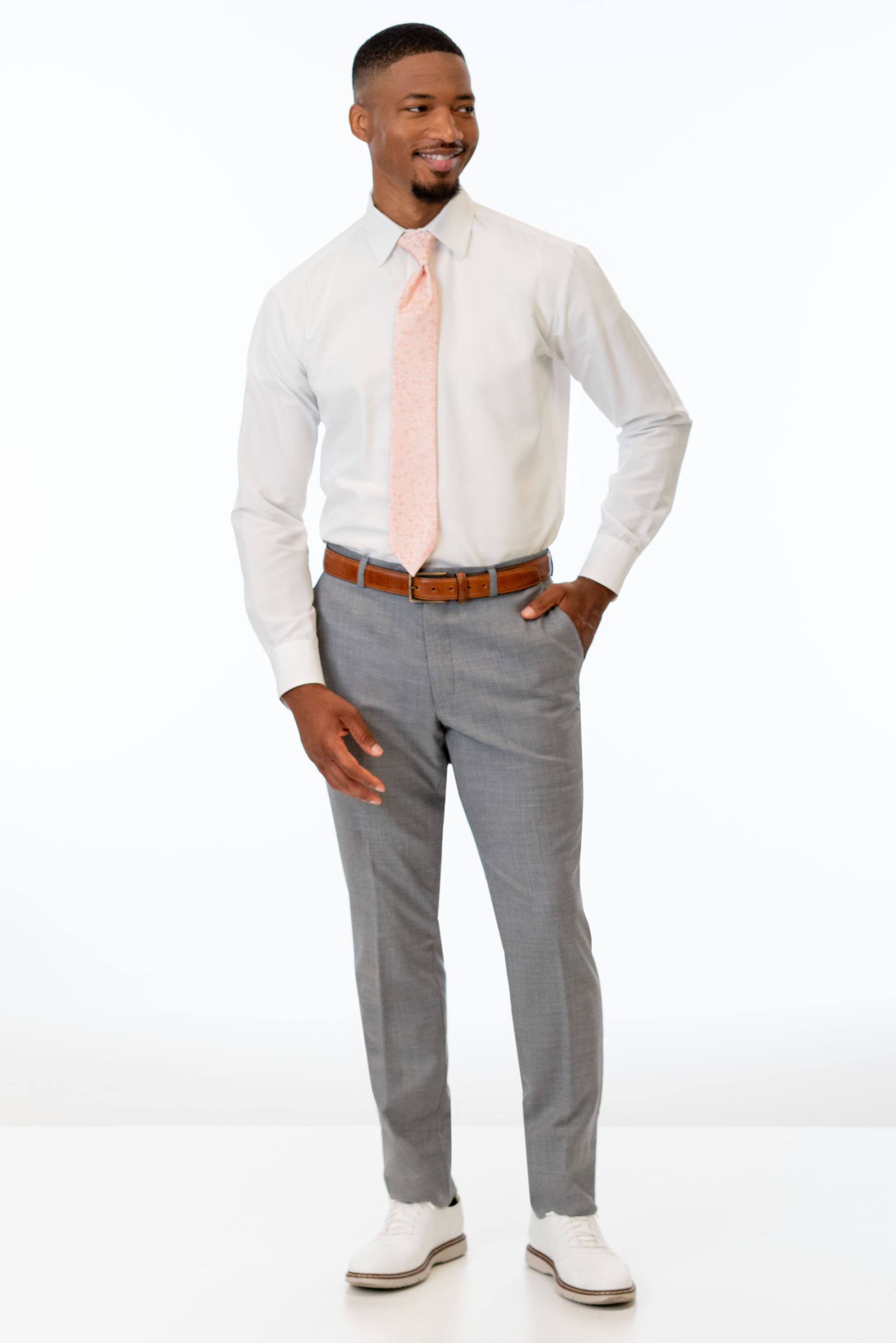 Man wearing Heather Grey Clayton pants with a white shirt and pink tie on a white background