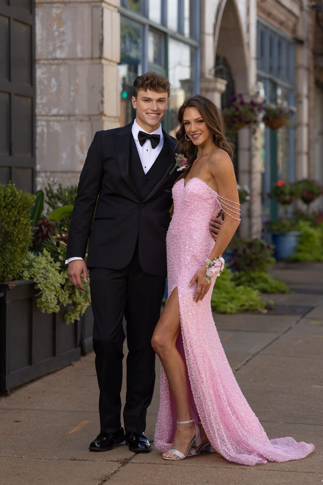 prom guy in black tux and teardrop bow tie with prom girl in pink strapless gown