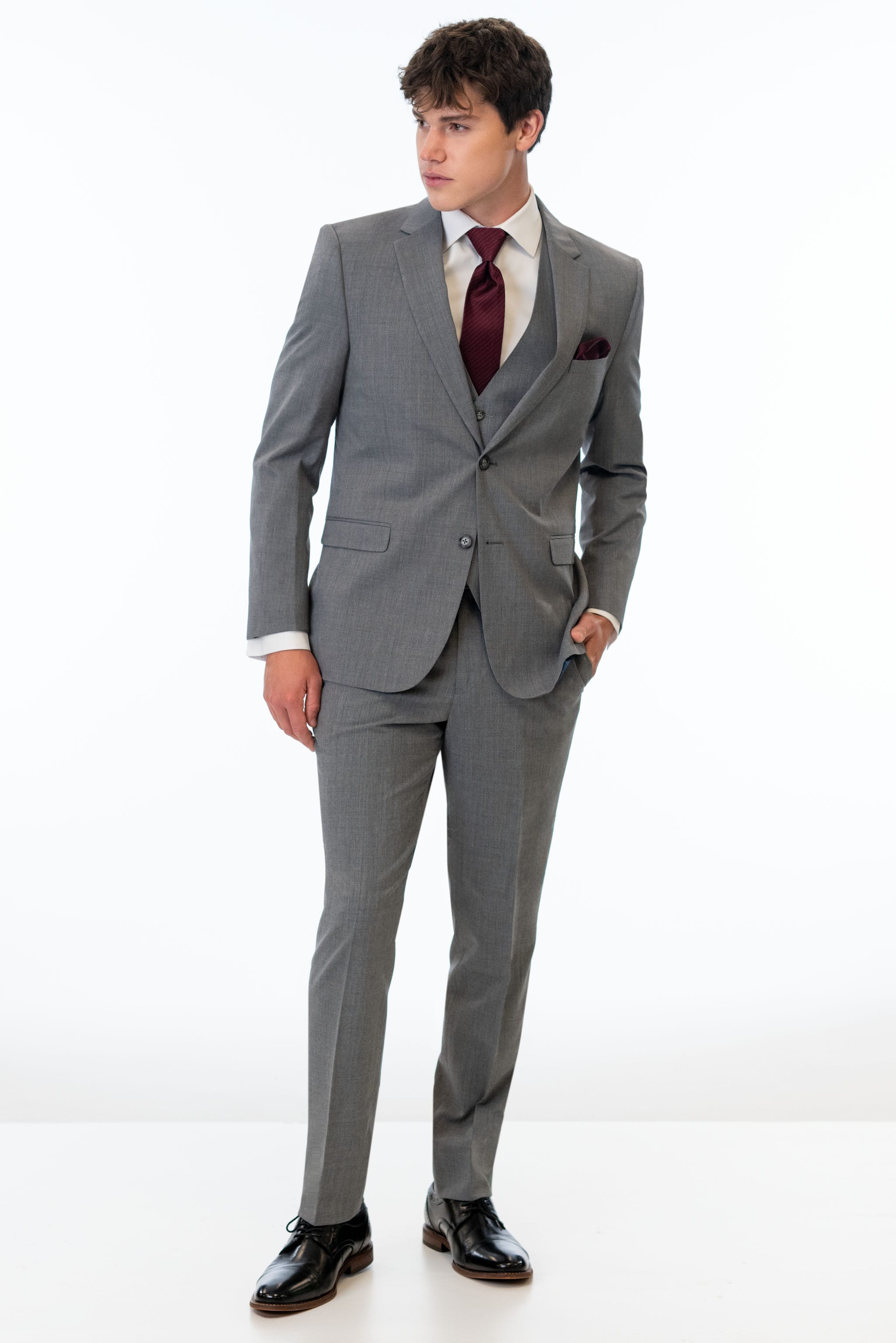 Man wearing a Medium Grey Performance Stretch suit with a red tie on a white background