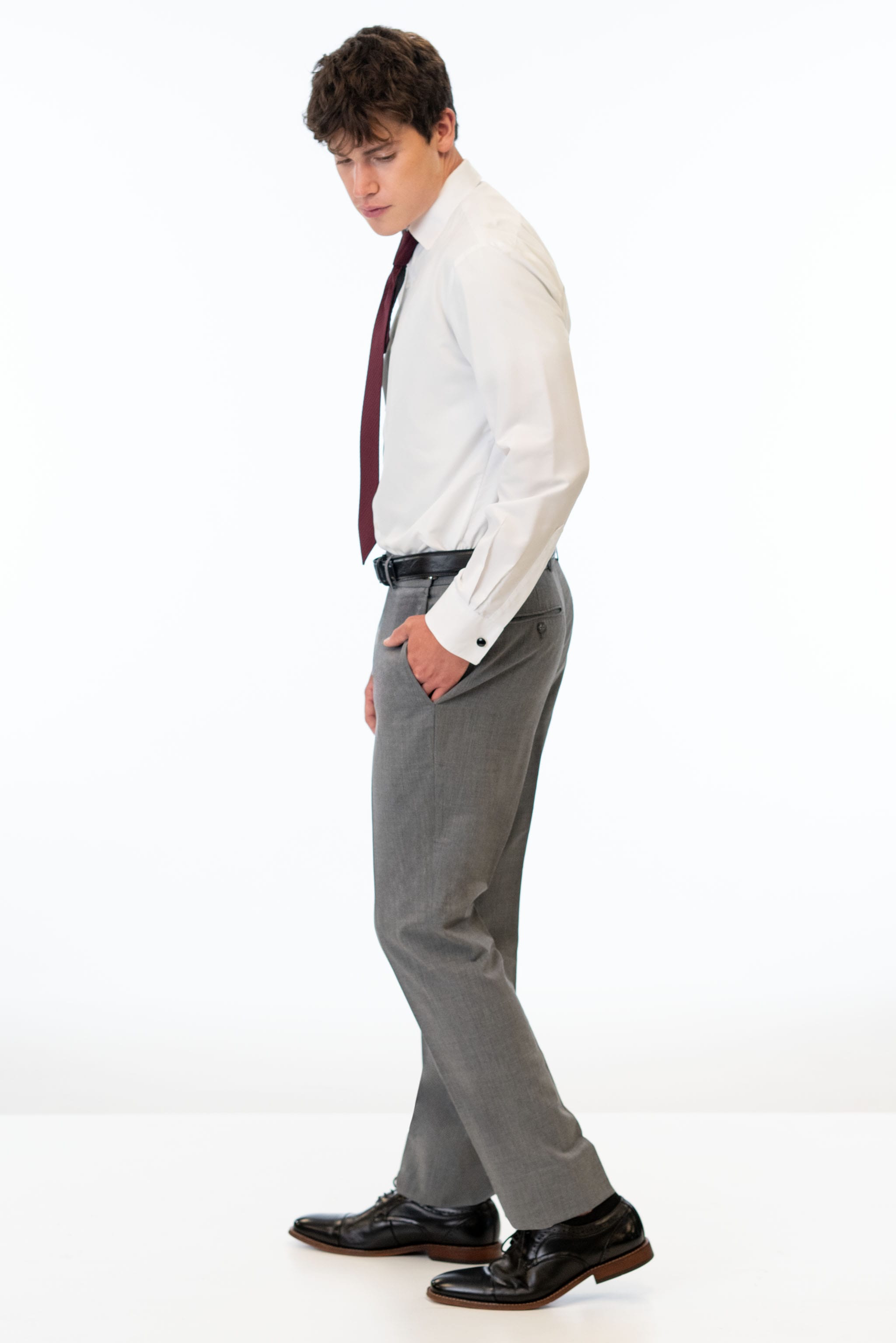 side view of man wearing Medium Grey Performance Stretch Slim Fit pants, white shirt, and windsor tie