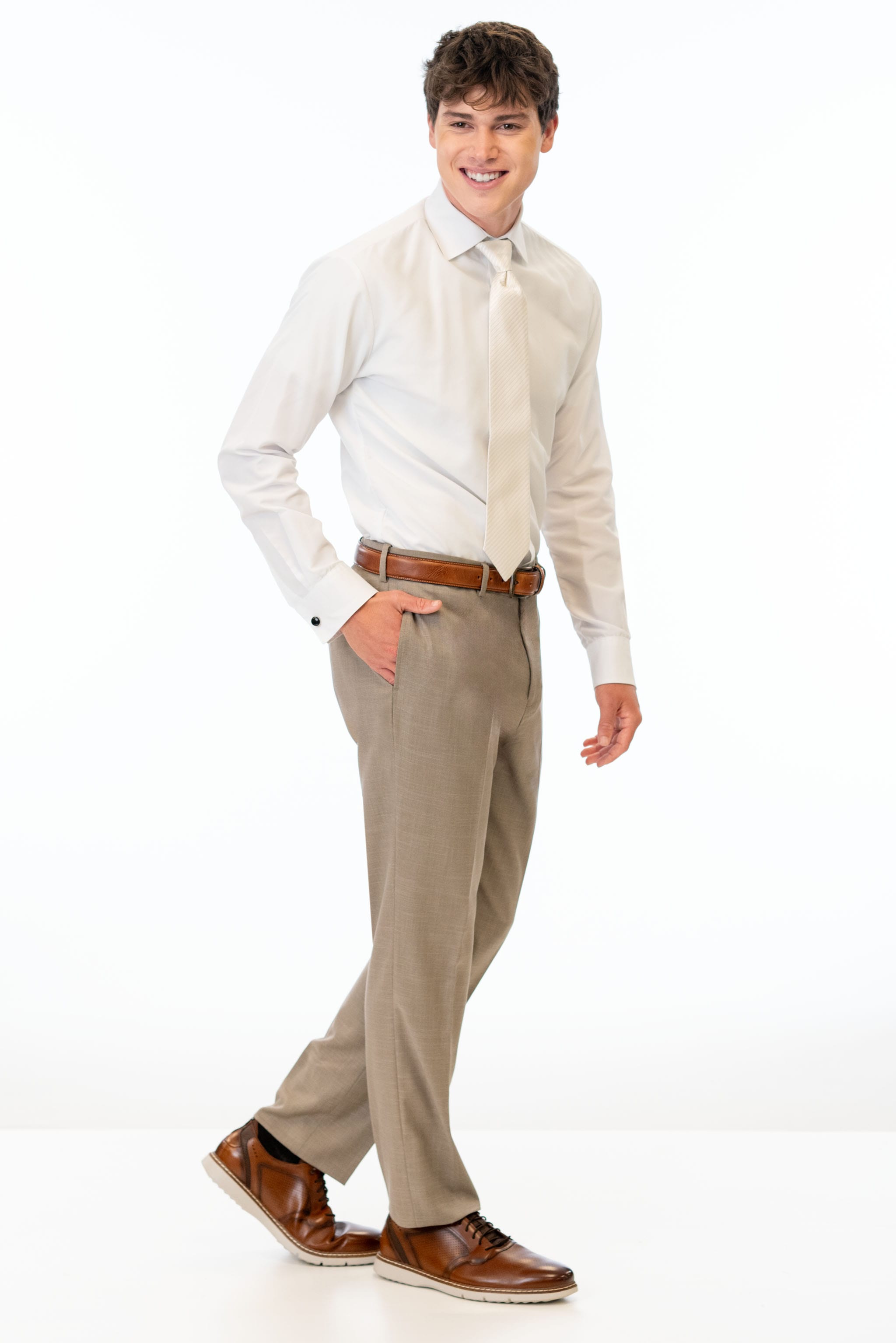 side view of man wearing Wheat Stretch Slim Fit Suit pants, white shirt, and ivory tie
