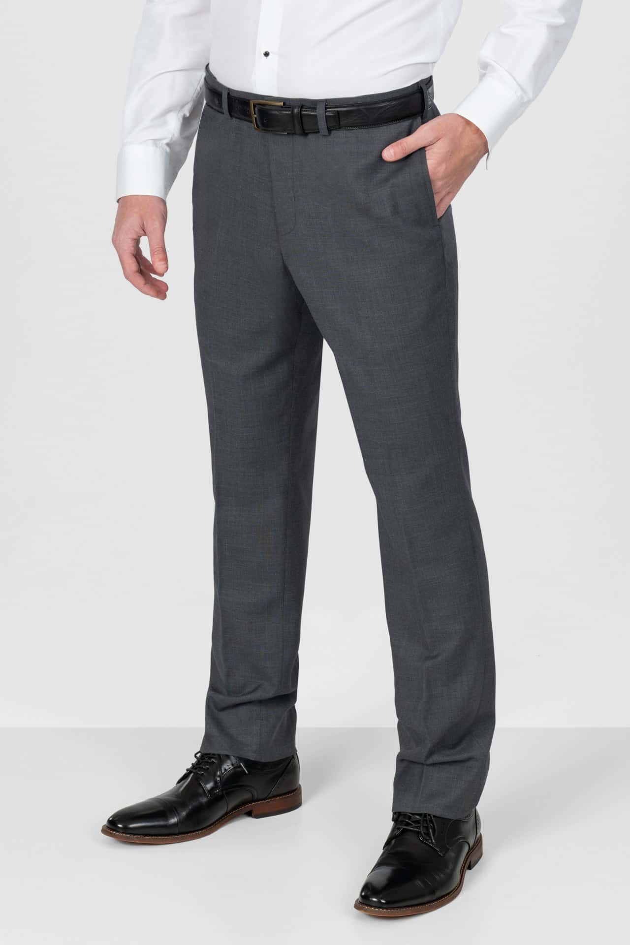 Person wearing slate grey dress pants with a white shirt and black shoes on a white background
