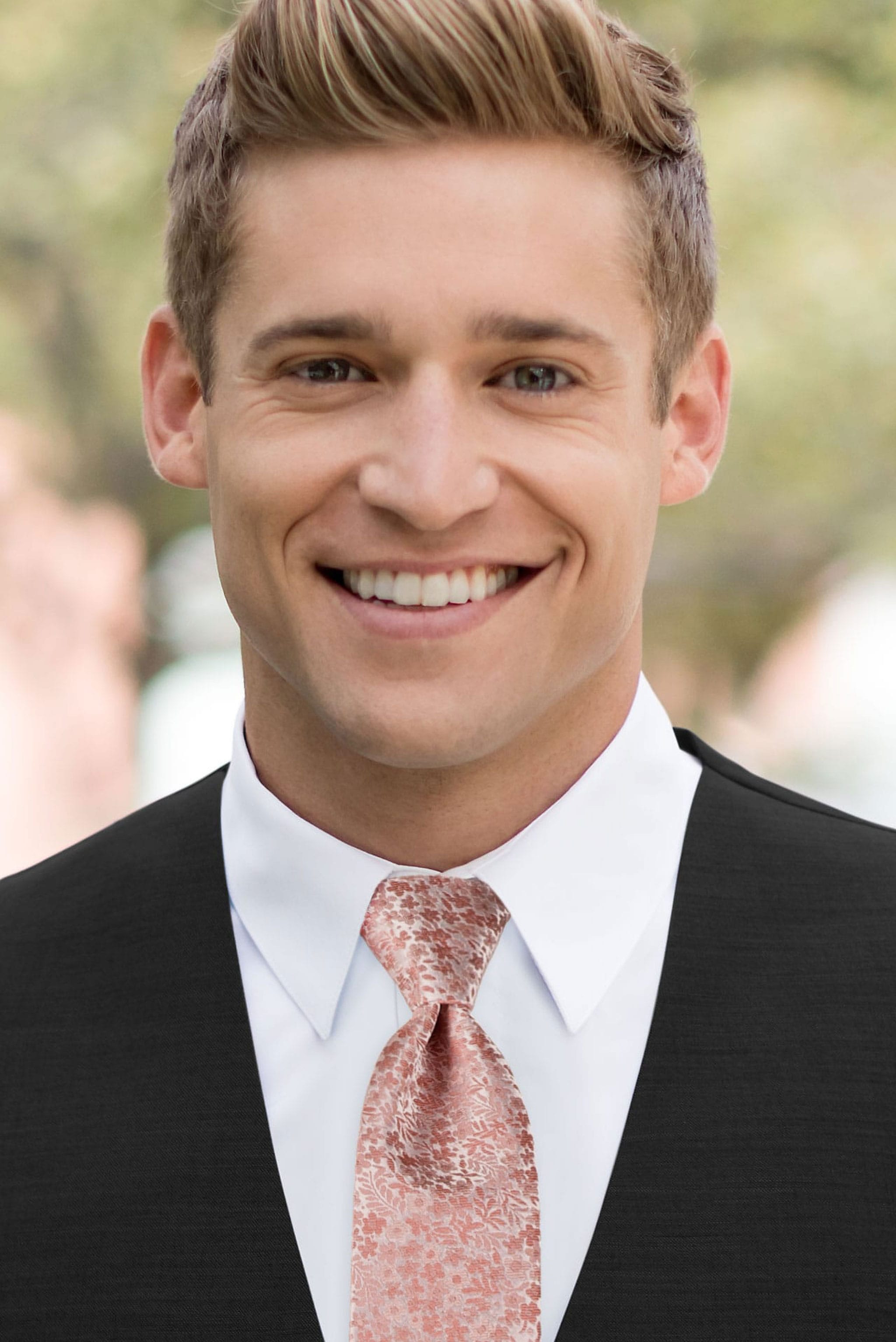 Man wearing a black suit with a white shirt and dusty coral floral windsor tie