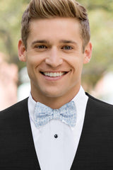 man wearing white shirt, floral dusty blue bow tie and solid black Expressions vest