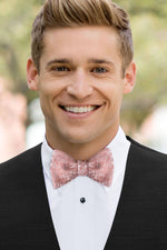 man wearing white shirt, floral dusty coral bow tie and solid black Expressions vest