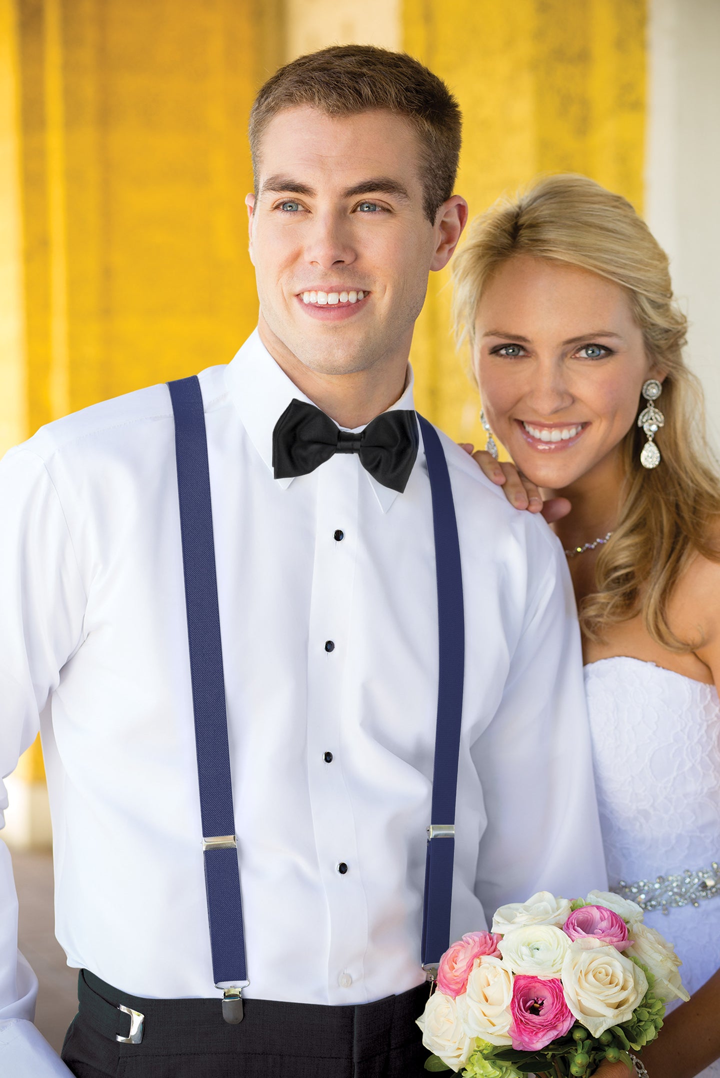 Man wearing white shirt, men’s blue clip-on suspenders, and coordinating blow tie